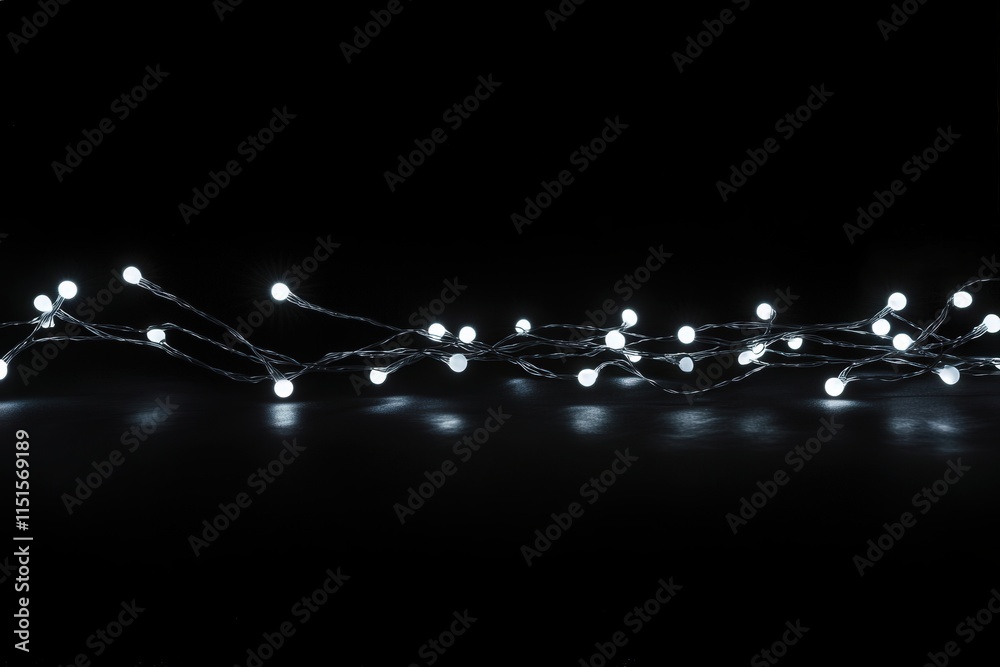 A string of illuminated, small white bulbs weaves through a dark setting, casting soft light and enhancing the cozy ambiance of the evening. The orderly design adds warmth to the surrounding space.