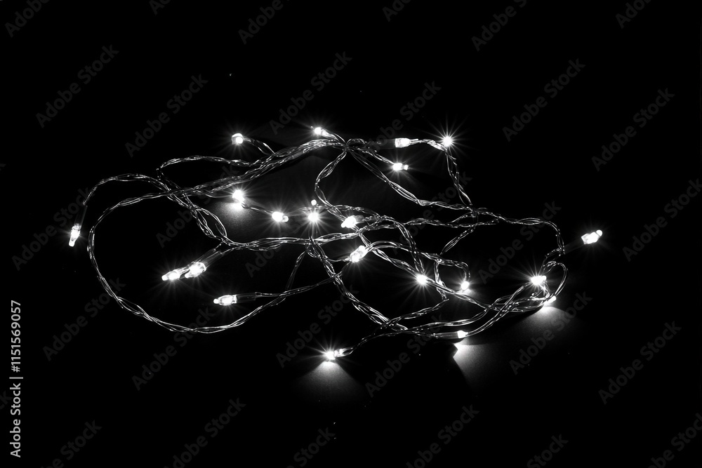A tangled arrangement of twinkling white string lights sits against a black backdrop, creating a cozy ambiance. The scene captures the essence of nighttime warmth and festivities.