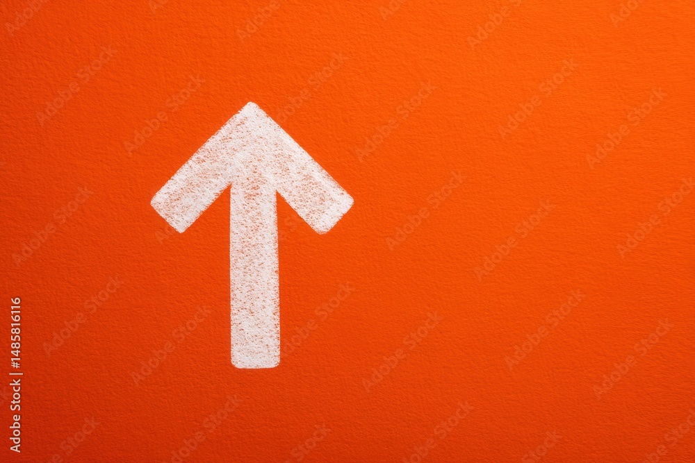 A large white arrow is painted on a vibrant orange wall, directing attention upwards. This striking design element enhances the visual appeal and guides viewers focus.
