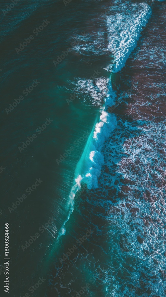 Turquoise waves roll and crash against the shoreline, creating foam as they meet the sand. The sun sets, casting a warm glow over the tranquil ocean surface, reflecting natures beauty.